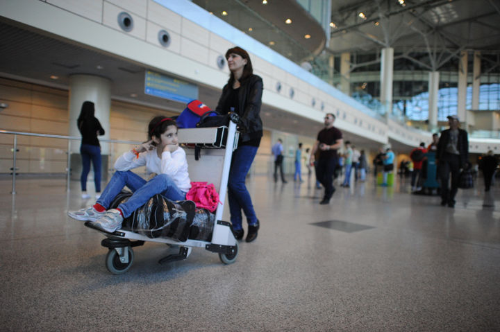 ребенок в багажной тележке в аэропорту